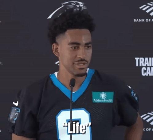 a man in a panthers jersey is talking into a microphone and says " what a beautiful thing "