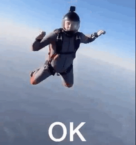 A Man In A Parachute Suit Is Flying Through The Air With The Word Ok . GIF