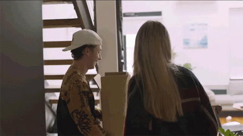 A Man In A Patagonia Shirt Is Talking To A Woman In A Living Room GIF