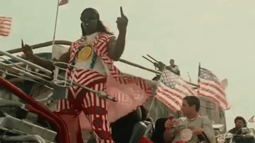 A Man In A Patriotic Outfit Is Giving The Middle Finger While Riding A Motorcycle . GIF