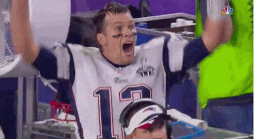 A Man In A Patriots Jersey Is Raising His Hands In The Air . GIF