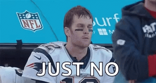 a man in a patriots jersey is sitting in a dugout with the words just no written on his face .