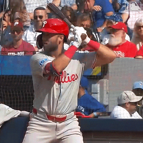 A Man In A Phillies Uniform Is Swinging At A Baseball GIF