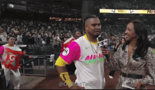 A Man In A Pink And Yellow Jersey Is Being Interviewed By A Female Reporter GIF