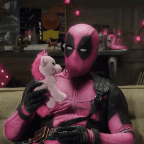 A Man In A Pink Deadpool Costume Is Holding A Pink Unicorn GIF