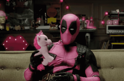 A Man In A Pink Deadpool Costume Is Holding A Stuffed Pink Unicorn GIF