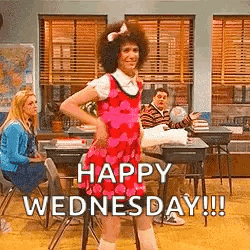 A Man In A Pink Dress Is Standing In A Classroom With A Group Of People Sitting At Desks . GIF