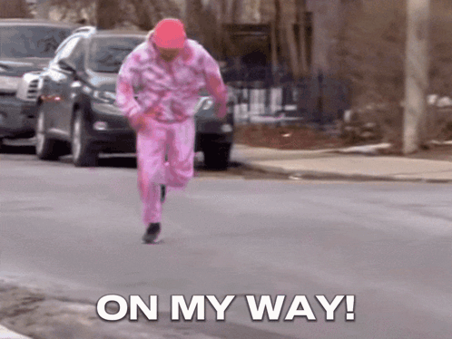A Man In A Pink Outfit Is Running Down The Street With The Words On My Way GIF