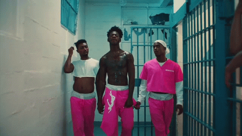 A Man In A Pink Prison Uniform Is Walking With Two Other Men GIF