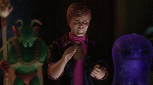 A Man In A Pink Scarf Is Standing Next To A Purple Ghost GIF