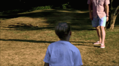 A Man In A Pink Shirt And Shorts Stands Next To A Girl In A White Shirt GIF