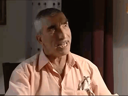 A Man In A Pink Shirt Has A Cross On His Pocket GIF