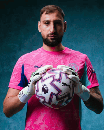A Man In A Pink Shirt Holds A Soccer Ball With The Word Premier League On It GIF