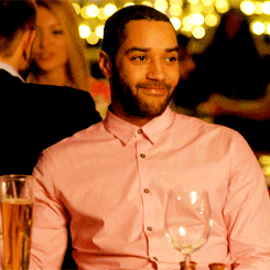 A Man In A Pink Shirt Holds A Wine Glass GIF