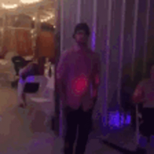 a man in a pink shirt is dancing on a dance floor in a room .