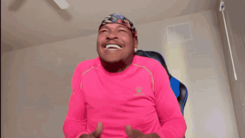 A Man In A Pink Shirt Is Holding A Game Controller And Laughing GIF