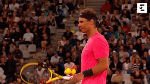 A Man In A Pink Shirt Is Holding A Tennis Racket And Balls . GIF