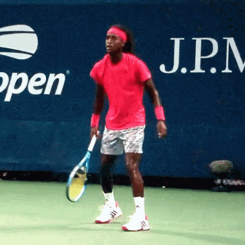 A Man In A Pink Shirt Is Holding A Tennis Racquet In Front Of An Open Sign GIF