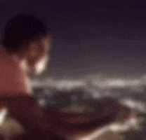 a man in a pink shirt is looking out over a body of water at night