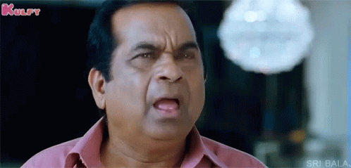 A Man In A Pink Shirt Is Making A Funny Face And Looking At The Camera . GIF