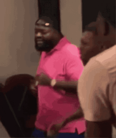 A Man In A Pink Shirt Is Running On A Treadmill With Other Men . GIF