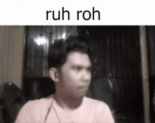 A Man In A Pink Shirt Is Sitting In Front Of A Screen That Says Ruh Roh GIF