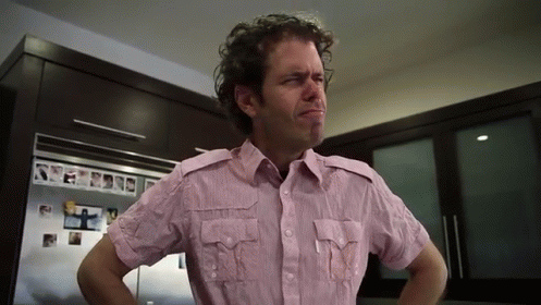 A Man In A Pink Shirt Is Standing In A Kitchen GIF