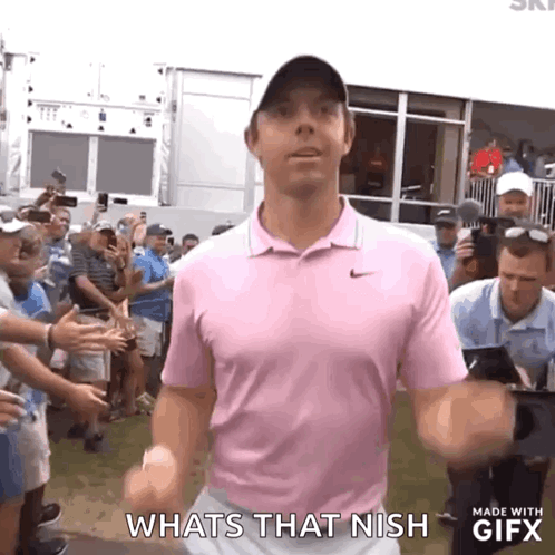 A Man In A Pink Shirt Is Standing In Front Of A Crowd And Says Whats That Nish . GIF