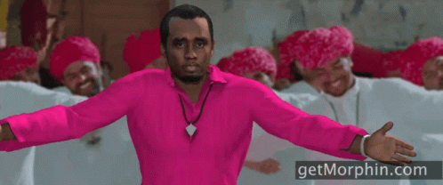 A Man In A Pink Shirt Is Standing In Front Of A Group Of Men Wearing Red Hats GIF