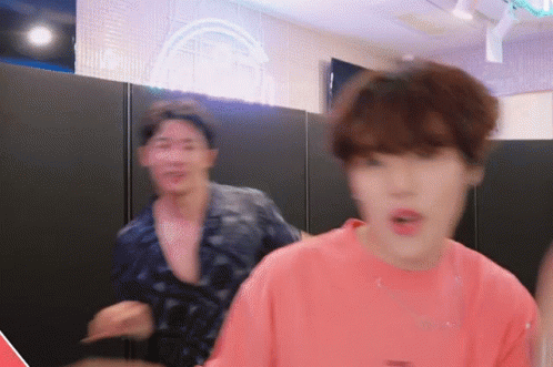 A Man In A Pink Shirt Is Standing Next To Another Man In A Black Shirt GIF