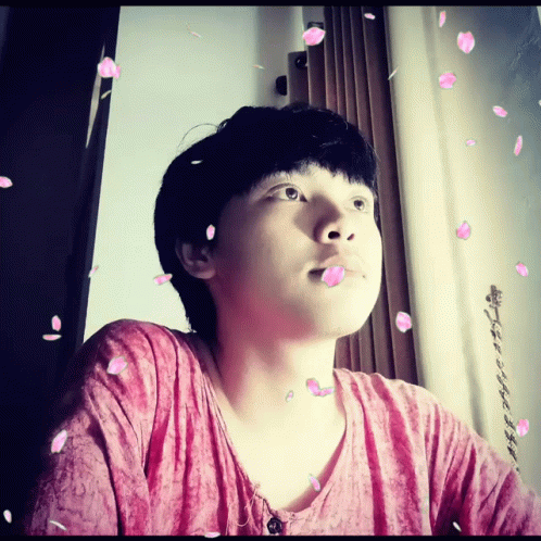 A Man In A Pink Shirt Is Surrounded By Petals GIF