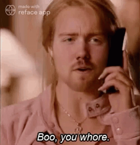 A Man In A Pink Shirt Is Talking On A Cell Phone And Says Boo , You Whore . GIF