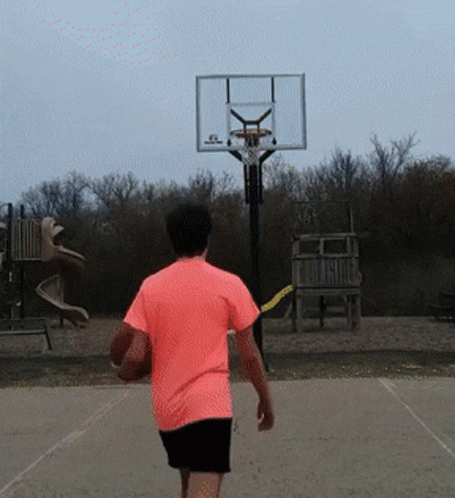 A Man In A Pink Shirt Is Walking Toward A Basketball Hoop GIF