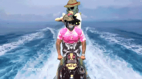 A Man In A Pink Shirt Rides A Jet Ski In The Ocean GIF