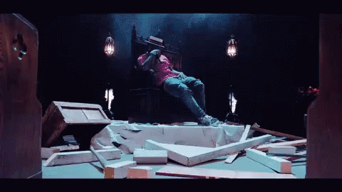 a man in a pink shirt sits on a throne