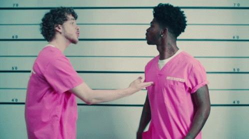 A Man In A Pink Shirt With A Tattoo On His Neck Stands Next To Another Man In A Pink Shirt GIF