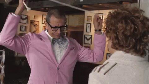A Man In A Pink Suit And Bow Tie Is Dancing With Another Man . GIF