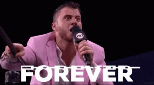 A Man In A Pink Suit Is Holding A Microphone And Shouting Into It . GIF