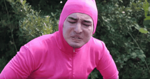 A Man In A Pink Suit Is Making A Funny Face With His Eyes Closed GIF