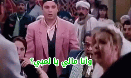 A Man In A Pink Suit Is Standing In A Crowd Of People And Talking To A Woman . GIF