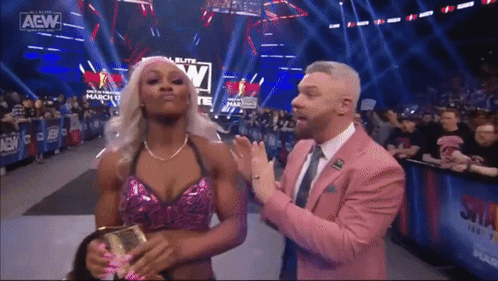 A Man In A Pink Suit Is Standing Next To A Woman In A Pink Top . GIF
