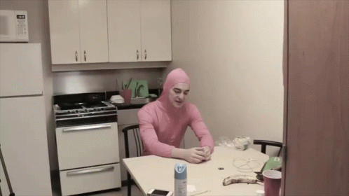 A Man In A Pink Suit Sits At A Table GIF