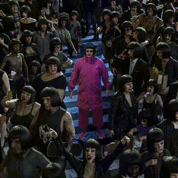 A Man In A Pink Suit Stands In The Middle Of A Crowd GIF