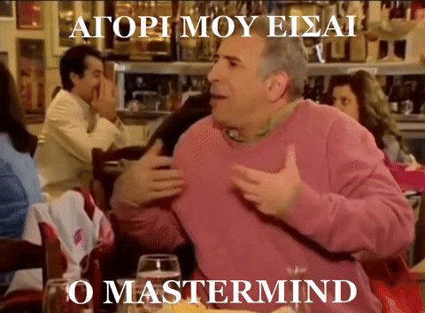 A Man In A Pink Sweater Is Sitting At A Table In Front Of A Sign That Says O Mastermind GIF
