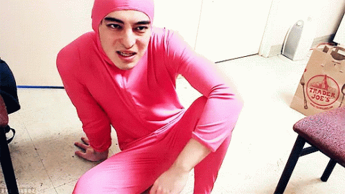A Man In A Pink Trader Joe 'S Outfit Is Squatting On The Floor GIF