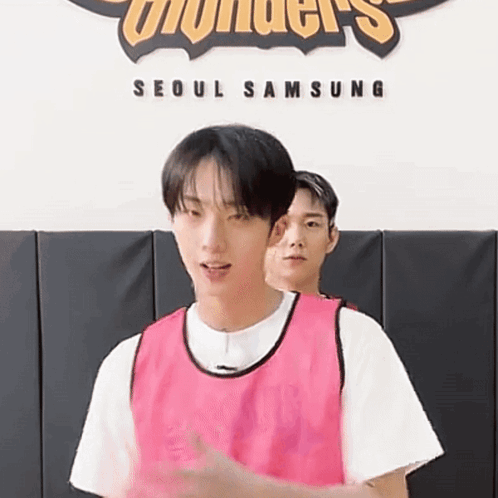 A Man In A Pink Vest Is Standing Next To Another Man In A White Shirt . GIF
