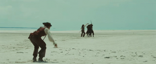 A Man In A Pirate Costume Is Walking On A Beach GIF