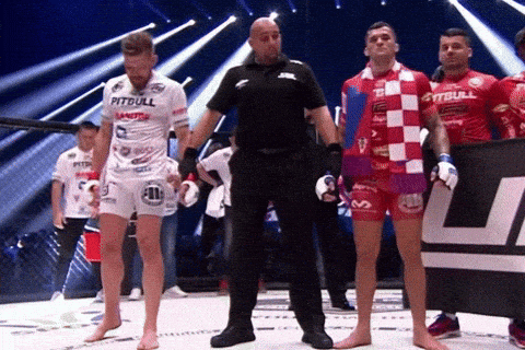 A Man In A Pitbull Shirt Stands Next To A Referee GIF