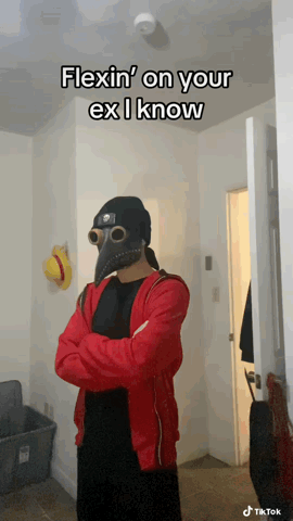 A Man In A Plague Doctor Mask Is Standing In A Hallway With His Arms Crossed GIF