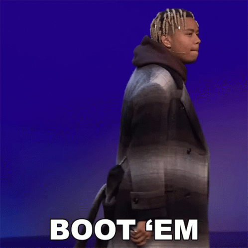 A Man In A Plaid Coat Is Walking With The Words Boot 'Em Behind Him GIF